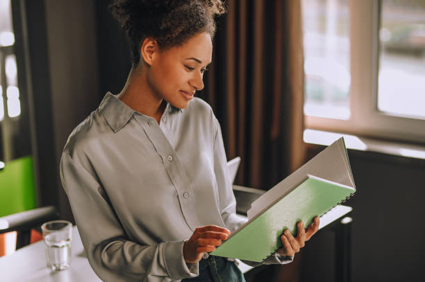 istock Young curly-haired woman scrutinizing the project papers 1360494585