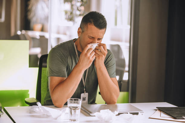 istock Office worker sitting at the table and sneezing 1360494643