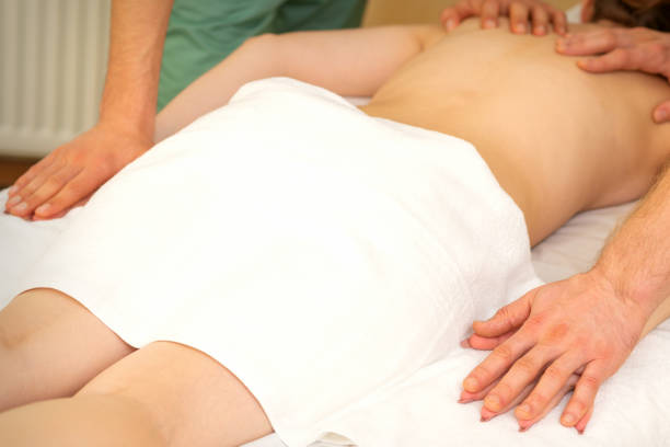 istock Back and hands double massage with four hands of two professional massagers for a young caucasian woman in a spa salon. 1360494725
