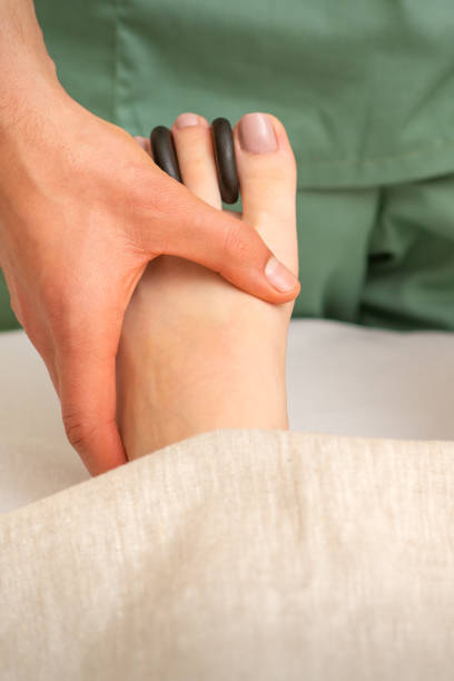 istock Massager doing feet and toes massage with rocks between a female toes. 1360494749