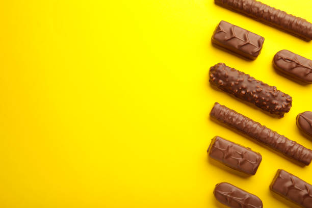 istock Mix of chocolate bars on yellow background. Top view. 1360495615