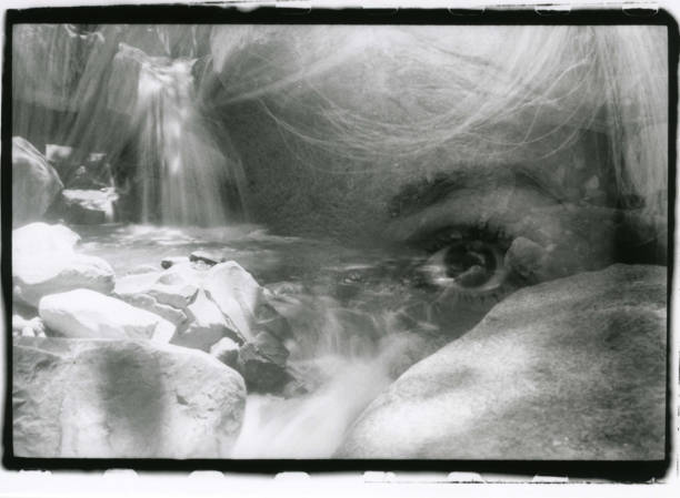 Multiple exposure: a woman's eye and a landscape with a waterfall in one shot. Attention! The image contains grain and other analog photography artifacts!