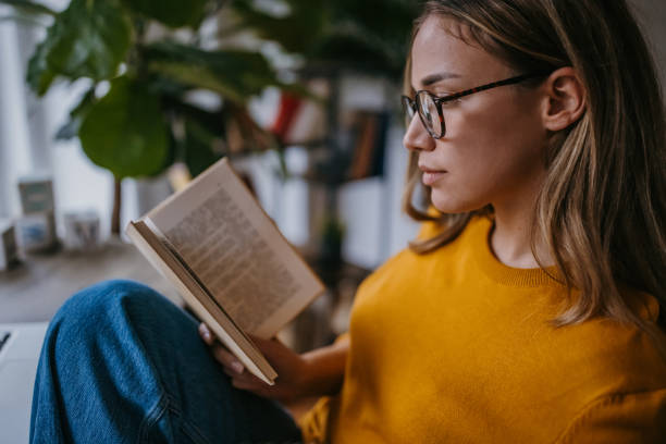istock Young woman reading a book 1360498712
