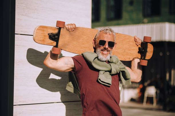 istock Joyful mature skateboarder smiling at the camera 1360498825