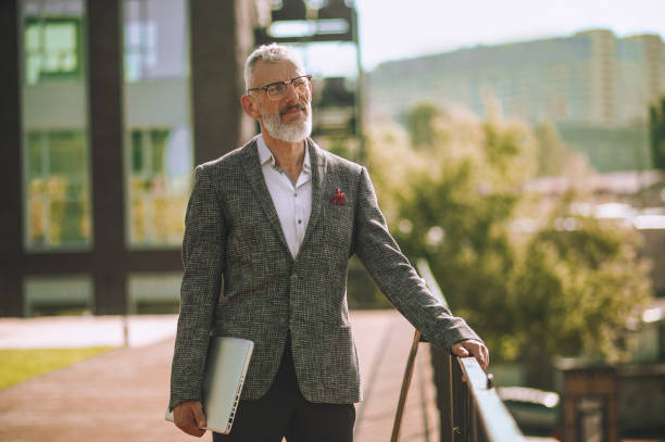 istock Calm elegant man with the laptop looking into the distance 1360498861