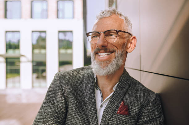 istock Smiling joyous mature businessman leaning against the wall 1360498917