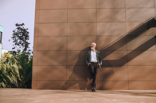 istock Joyful bearded gray-headed man standing outdoors and looking away 1360498927