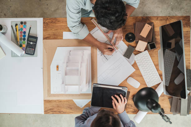 istock Team architect design building model with blueprint engaged working together on the desk in office. 1360498983