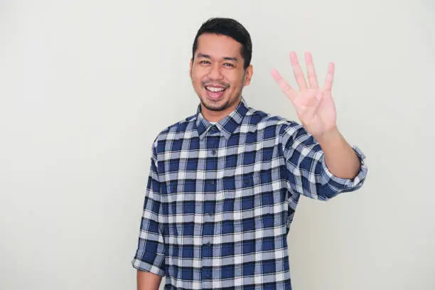 Photo of Adult Asian man smiling happy while showing four fingers sign