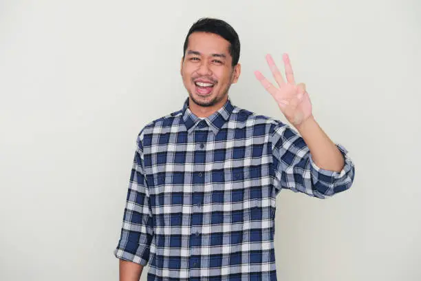 Photo of Adult Asian man smiling happy while showing three fingers sign