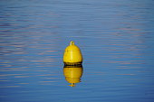 istock Yellow buoy on blue water surface 1360506891