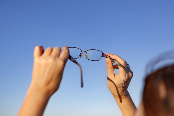 istock Hands hold eyeglasses on sky background at sunset. Madrid, Spain 1360506988