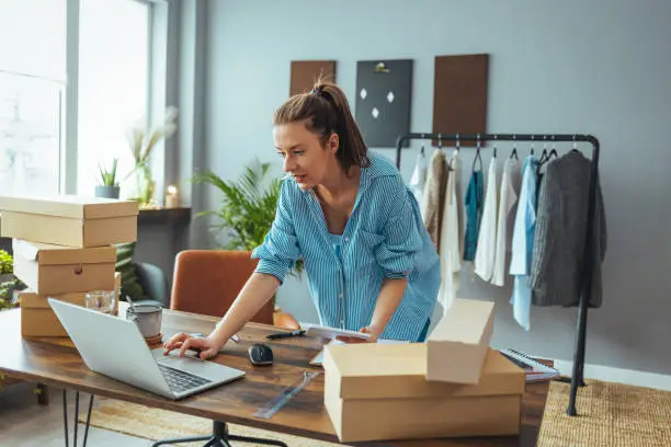 Photo of Women, owener of small business packing product in boxes