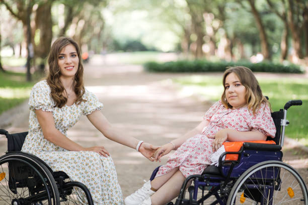 istock Smiling women in wheelchairs holding hands at park 1360508080