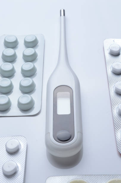 istock tablets in a package and a white electronic thermometer on a white surface close-up. 1360509095