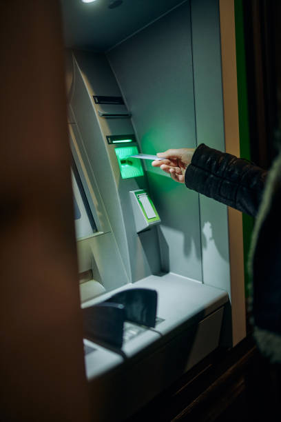 istock Woman using ATM machine outdoors 1360510457