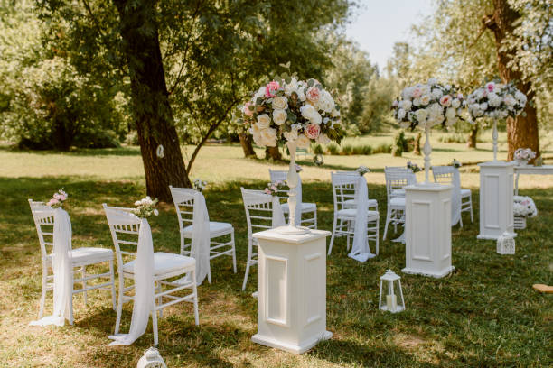 istock Wedding ceremony outdoors in the park. White chairs decorated with roses. 1360510708