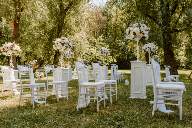 istock Wedding ceremony outdoors in the park. White chairs decorated with roses. 1360510737