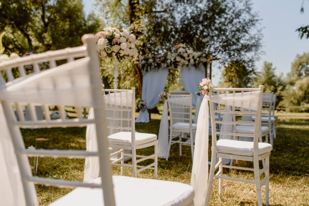 istock Wedding ceremony outdoors in the park. White chairs decorated with roses. 1360510761