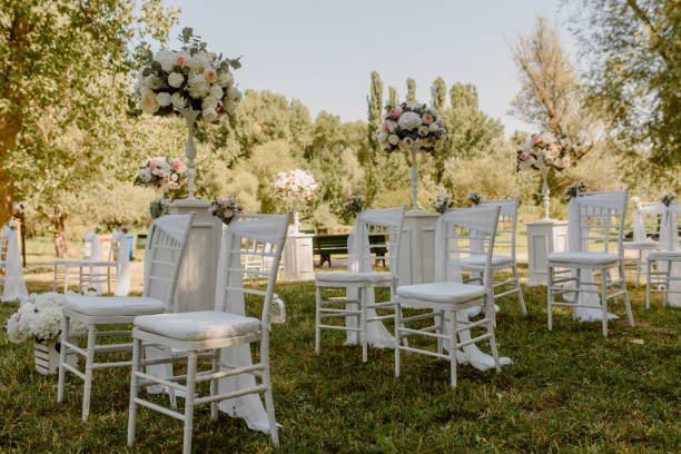 istock Wedding ceremony outdoors in the park. White chairs decorated with roses. 1360511323