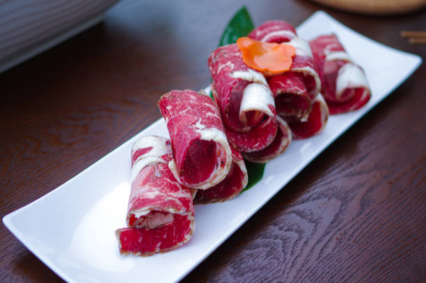 Sliced raw beef rolls on white plate for hot pot Sliced raw beef rolls on white plate for hot pot.
Hot pot or hotpot, also known as soup-food or steamboat, is a cooking method that originated in China, prepared with a simmering pot of soup stock at the dining table, containing a variety of Chinese foodstuffs and ingredients. mutton roll for chinese hot pot stock pictures, royalty-free photos & images