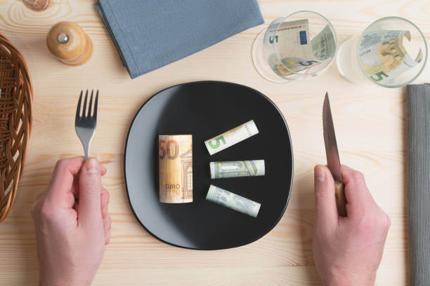 Conceptual studio shot of dinner table with euro bank notes on the plate instead of food. Concept for rising food prices, inflation, economic crisis, consumer prices index. stock photo