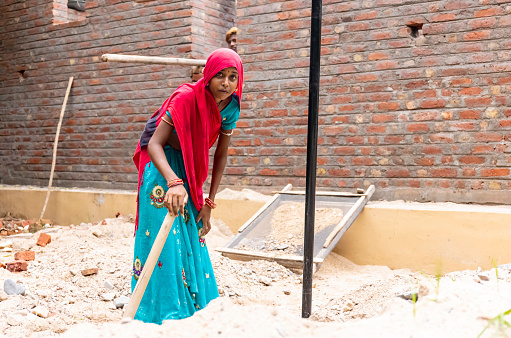 Jawai, Rajasthan, India - September 2021: Portrait of indian woman working at construction site in ethnic rajasthani dress. Indian labour at working site.