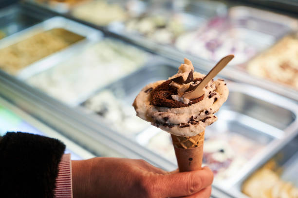 istock a hand holding an ice cream in front of a display case 1360518899