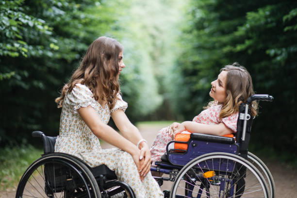 istock Women with physical disability chatting at summer park 1360519073