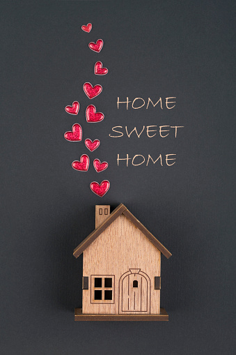 Wooden house  and  red heart shape on black background with text ,,Home sweet home
