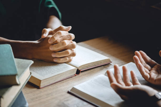 Christian group of people holding hands praying worship to believe and Bible on a wooden table for devotional or prayer meeting concept."n stock photo