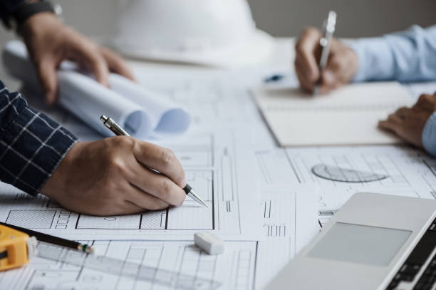 istock close up of team engineer or architect meeting for project working with partner and engineering tools on model building and blueprint in working site. Construction concept 1360521418