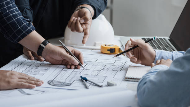 istock close up of team engineer or architect meeting for project working with partner and engineering tools on model building and blueprint in working site. Construction concept 1360521442