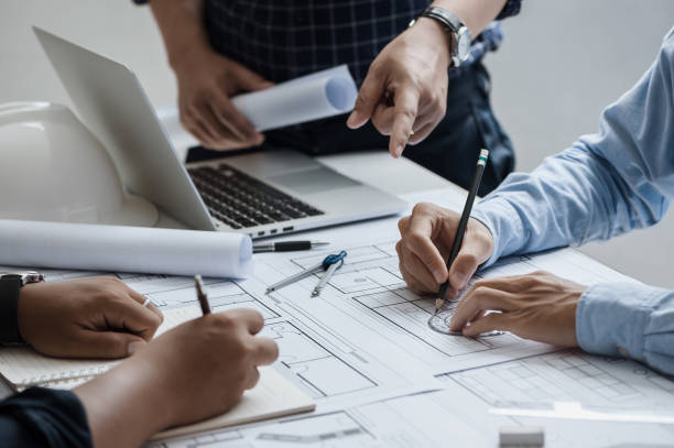 istock close up of team engineer or architect meeting for project working with partner and engineering tools on model building and blueprint in working site. Construction concept 1360521445