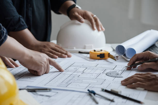 istock close up of team engineer or architect meeting for project working with partner and engineering tools on model building and blueprint in working site. Construction concept 1360521447