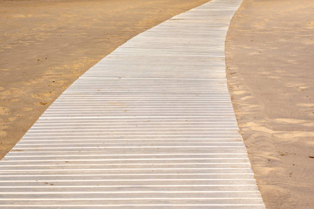 istock Wooden beach white boardwalk with sand for background 1360529012