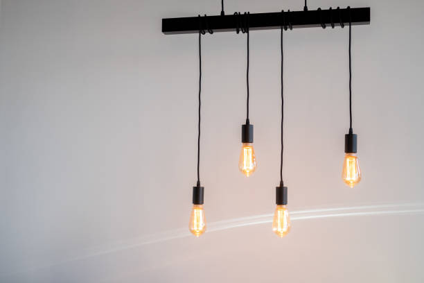 quatro lâmpadas penduradas no teto contra uma parede de cor clara - warm light - fotografias e filmes do acervo