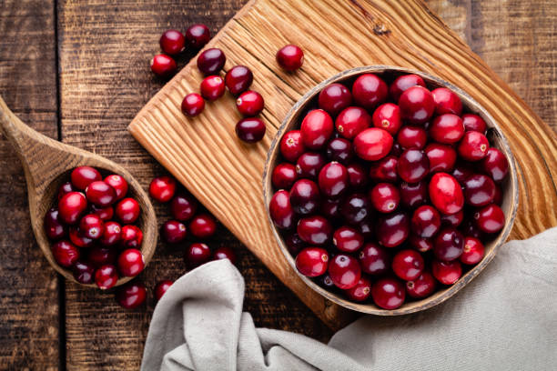 istock Red cranberries on wooden background. Brries in a bowl. 1360531479