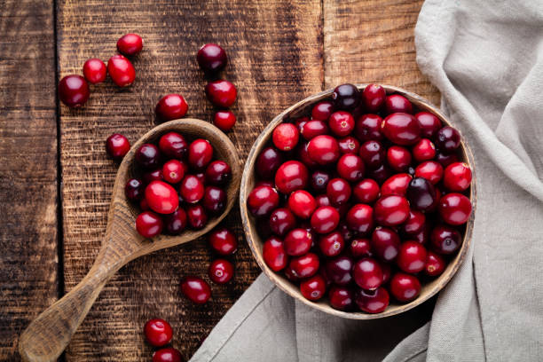 istock Red cranberries on wooden background. Brries in a bowl. 1360531511
