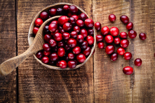 istock Red cranberries on wooden background. Brries in a bowl. 1360531513
