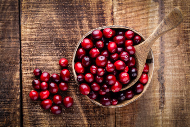 istock Red cranberries on wooden background. Brries in a bowl. 1360531533