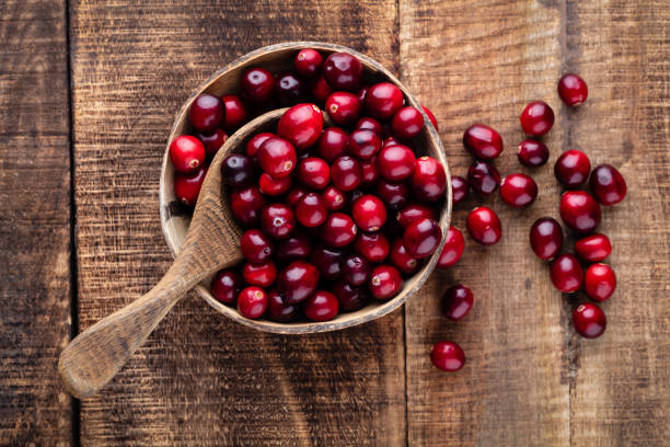 istock Red cranberries on wooden background. Brries in a bowl. 1360531534
