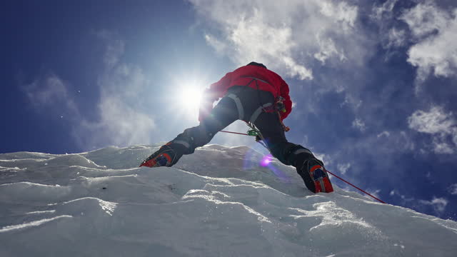 Equipped mountaineer climb over ice wall. Crystalline pieces falling from above