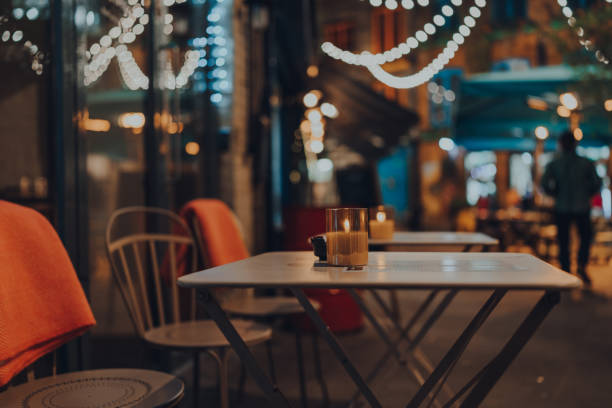 Lit candle at an outdoor table of a restaurant, Christmas lights on the background. stock photo