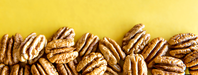 Pecan nuts shelled on yellow background.