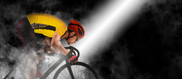Man racing cyclist in motion on smoke background. Man in yellow cycling jersey.  Sports banner. Horizontal copy space background