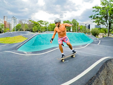 Adult man riding a skateboard on an asphalt track at Parque das Bicicletas, a Bicycles' Park in the city of São Paulo, State of São Paulo, Brazil, December 10, 2021