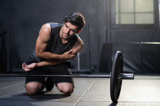 junge kaukasische männer packen seinen arm und seine schulter und fühlen sich schmerzhaft beim gewichtheben im sportgymnastik. sportunfall, übertraining. - shoulder pain physical injury muscular build stock-fotos und bilder