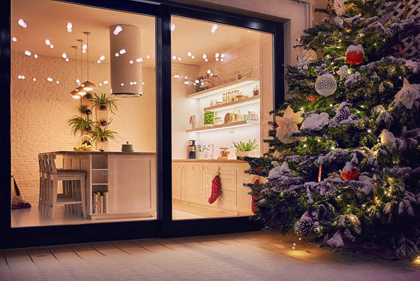 cozy apartment with sliding doors, and decorated christmas tree on the patio at snowy winter night - window christmas night house imagens e fotografias de stock