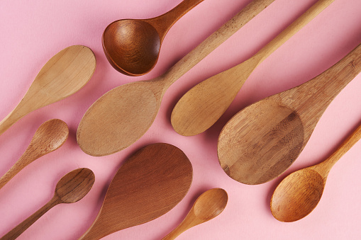 Different wooden spoons on pink background , spoons of different wood